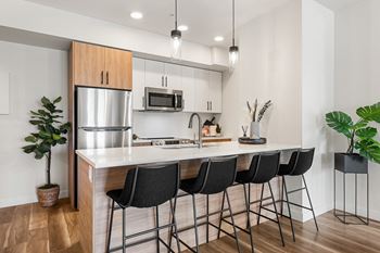 a kitchen with an island with bar stools and a stainless steel refrigerator